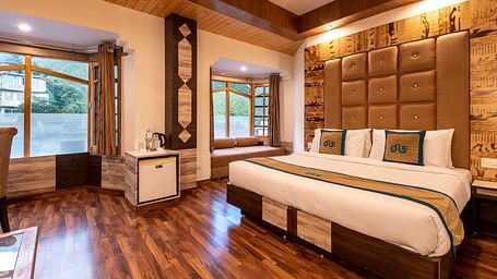 A hotel room in Bhagsunag featuring a large bed, wooden floors, a wooden ceiling, and windows with a view - DLS Meghavan Resort